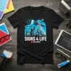 Black t-shirt featuring "SIGNS 4 LIFE" text and a skeleton hand painting a city skyline with a paintbrush. Includes @GOSIGNGO