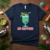 Sip Happens funny cocktail quote on a navy blue t-shirt with a cartoon illustration of a refreshing drink