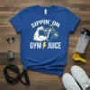 Blue t-shirt with white text "Sippin' On Gym Juice" and graphic of a muscular arm holding a shaker bottle with