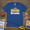 Blue t-shirt with "Sixth Grade" text and an owl reading a book, designed for back-to-school