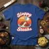 Sloppy Steaks t-shirt design featuring cartoon steaks being drenched in sauce with retro sunset background