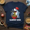 Slurpin' Good text with a cartoon chef shark eating ramen noodles, on a navy blue t-shirt