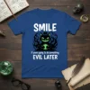 SMILE if youre going to do something EVIL LATER quote on a blue t-shirt with a grinning black cat graphic