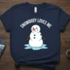 T-shirt with white text "Snowbody Loves Me" above a crying snowman graphic on a navy blue shirt