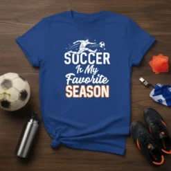 Blue t-shirt with white and orange text "SOCCER Is My Favorite SEASON" and a graphic of a soccer player kicking