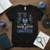 Black t-shirt with "Solar System Planets Universe" text and scientific diagrams including atoms, galaxies, and humans