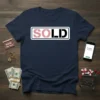 Navy blue t-shirt with the word "SOLD" in pink and black text inside a white-bordered rectangle