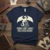 Sorry Can't Adult Busy Slaying Dragons text design with a dragon and D20 dice graphic on a navy t-shirt