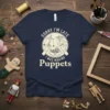 Navy blue t-shirt with "Sorry I'm Late I Was Making Puppets" text and a circular graphic of hands making puppets