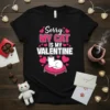 Sorry My Cat Is My Valentine text with white cat on pink cushion graphic, surrounded by pink hearts on black