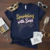 Sparkling with Sass quote on a navy t-shirt with fireworks graphic, gold and pink lettering, festive theme