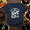 Spin The Black Circle Vinyl Collector T-Shirt featuring a graphic of hands placing a needle on a vinyl record