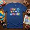 Spoiled By My Au Pair t-shirt featuring colorful text and a cute sun and bird graphic
