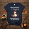 Spooky Goose On The Loose T-Shirt with a cute goose wearing a witch hat, holding a pumpkin, and a black