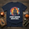Navy t-shirt with "Spooky Mansion Adventures" text and a graphic of a haunted house, ghosts, bats, and a sunset gradient