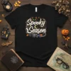 Spooky Season Halloween t-shirt design with a black cat, pumpkins, and bats. Features festive text in white and purple