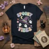 Spooky Vibes Halloween t-shirt with retro font, purple witch hat, cute ghosts, and pastel stars and flowers