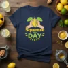 Navy t-shirt with yellow and green "Squeeze the DAY" text and a graphic of hands squeezing a lemon
