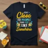 STAY Close TO PEOPLE WHO FEEL LIKE Sunshine quote on a navy t-shirt with floral and bird graphics