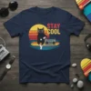 Stay Cool graphic t-shirt with a black cat wearing sunglasses, sitting by a boombox with a retro sunset background