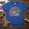 Blue t-shirt with "STAY GROOVY" text in colorful retro font, featuring a psychedelic mushroom and sunburst graphic