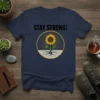 Stay Strong! text above a sunflower growing through cracked ground graphic, navy t-shirt design