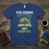 Stay Strong Your Story Isn't Over Yet quote on a navy blue t-shirt with an open book graphic