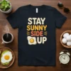 Stay Sunny Side Up quote t-shirt with a graphic of a sunny side up egg and bright, cheerful lettering