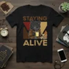 Black t-shirt with "STAYING ALIVE" text and a cartoon black cat holding a coffee mug, wearing a leather jacket