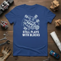 T-shirt with the phrase "STILL PLAYS WITH BLOCKS" and a graphic of an engine block with pistons