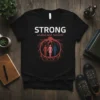 Black t-shirt with "STRONG united and resilient" text and root graphic embracing three figures, symbolizing community strength and unity