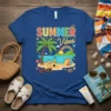 Summer Vibes text with a colorful beach scene including a palm tree, castle, and rainbow on a blue t-shirt