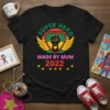 Black t-shirt with "SUPER HERO MADE BY MUM 2022" text and a shield graphic featuring a raised fist with a