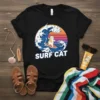 Black t-shirt with "Surf Cat" text and a cartoon cat surfing a large wave under a sunset