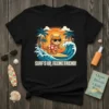 Surf's Up, Feline Friend! text on a t-shirt featuring a cat surfing a wave with palm trees and a sunset