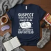 Navy t-shirt with white text: "SUSPECT CLAIMS SHE HAS SO much to do BUT LAYS DOWN TO NAP INSTEAD" and