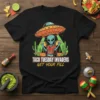 Taco Tuesday Invaders Get Your Fill t-shirt design with an alien holding tacos under a UFO, surrounded by cacti