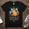Black t-shirt with an illustration of a cat using a computer, TAGGING MY CAT ON CAT MEMES
