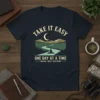 Take It Easy One Day At A Time t-shirt with a serene mountain and river landscape, a person meditating, and