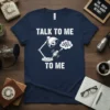 Navy t-shirt with white text "TALK TO ME TO ME" above a graphic of a desk lamp with an eye