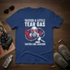 T-shirt with white text "Tasted a Little Tear Gas" above a gas mask graphic surrounded by barbed wire, and "Tasted