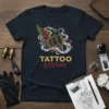 Tattoo Studio t-shirt with a colorful, winged tattoo machine graphic and smoke details