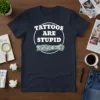 Navy t-shirt with white text "Tattoos Are Stupid" inside a circle and a tattooed arm graphic below