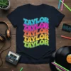 TAYLOR TAYLOR TAYLOR TAYLOR TAYLOR repeated in colorful retro wavy font on a navy t-shirt