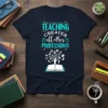 TEACHING CREATES all other PROFESSIONS! quote on a navy t-shirt, featuring an open book and a tree of knowledge graphic