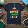 Teaching Future Leaders text with an owl on a book graphic on a navy blue t-shirt, symbolizing education and growth