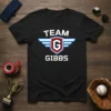 Black t-shirt with white "TEAM GIBBS" text and a shield logo with wings and the letter G