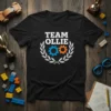 Black t-shirt with "TEAM OLLIE" text in white, surrounded by a laurel wreath and two gears, one blue and one