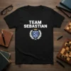 Black t-shirt with "TEAM SEBASTIAN" text and a blue shield logo with a crown and laurel wreath