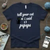 Tell Your Cat I Said Pspsps text with a black cat holding a megaphone graphic on a navy blue t-shirt